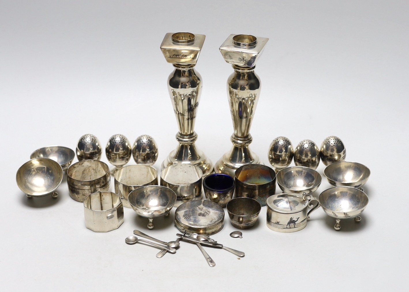 Thirteen assorted Iraq white metal and niello condiments, circular box, five similar napkin rings, a brooch and a pair of similar (damaged) candlesticks.